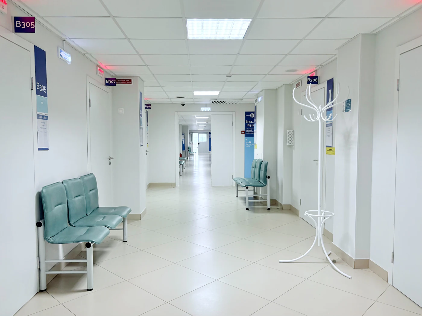 Empty hospital corridor with benches and doors — photo by Tasha Kostyuk on Unsplash