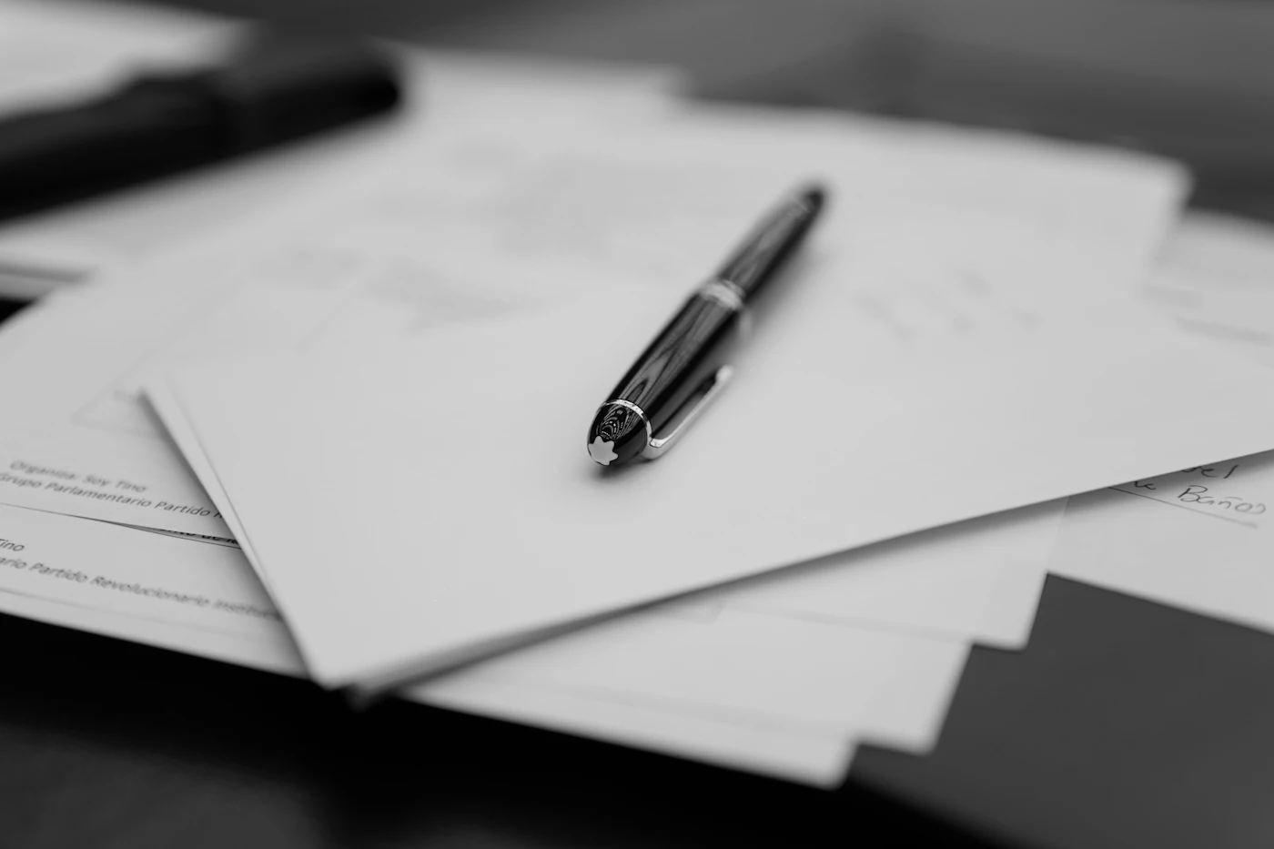 A pen sitting on top of a pile of papers — photo by Andres Vera on Unsplash